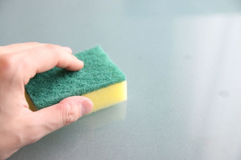 Hand cleaning a pane of glass with a sponge